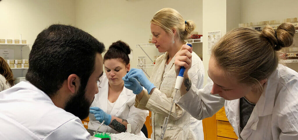 SMCC-Maine-students-in-lab-with-lab-coats-working-on-group-project