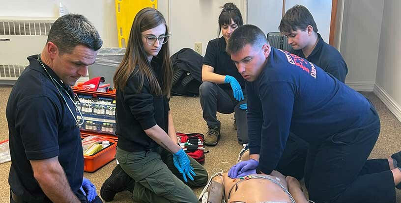 group-of-emergency-medical-services-students-with-dummy-and-equipment-SMCC-Maine